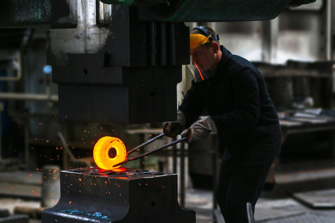 A worker shaping red-hot metal in a forge
